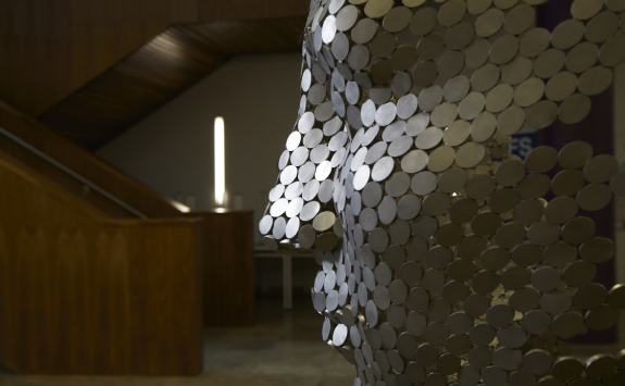 A sculpture of a face and neck formed in stainless steel circles